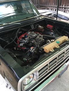 an old truck with its hood up and the engine in it