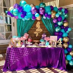 a table with purple, blue and green balloons in the shape of mermaids on it