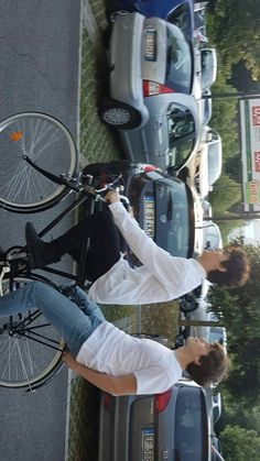 two people standing next to parked cars with bicycles on them