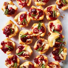 small appetizers with cranberry sauce and pecans are arranged on a white surface