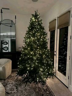 a living room with a christmas tree in the middle and lights on it's sides