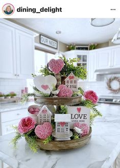 three tiered tray with pink flowers on top of a kitchen counter