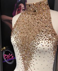 a white dress with gold sequins on it and a poster in the background