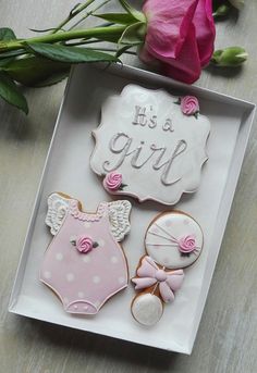 some cookies are in a box on a table next to flowers and a pink rose