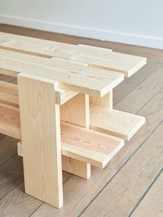 a bench made out of wooden planks sitting on top of a hard wood floor