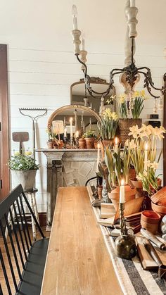 a wooden table topped with lots of vases filled with flowers next to a fire place