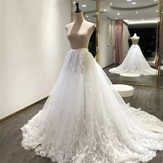 a white wedding dress on display in front of a mirror and mannequins