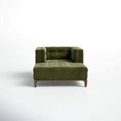 a green chair sitting on top of a white floor next to a wooden legrest