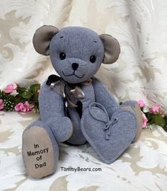 a blue teddy bear sitting on top of a bed with pink flowers in the background