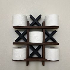 several rolls of toilet paper are arranged on a wooden shelf in front of a white wall