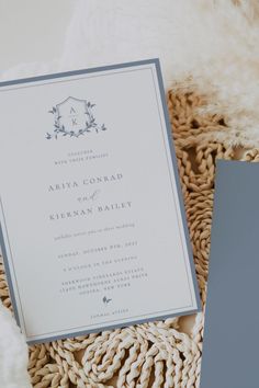 the wedding stationery is laid out on top of a woven blanket with a fur ball