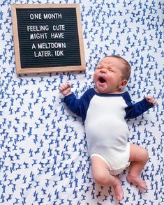 a baby laying on its back next to a sign that says, one month feeling cute might have a meltdown later