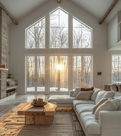 a large living room with high ceilings and windows overlooking the woods in front of it