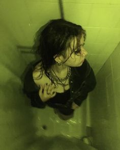 a woman in black shirt sitting on top of a urinal next to a toilet