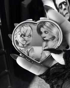 a person holding a compact mirror with the image of two evil clowns on it