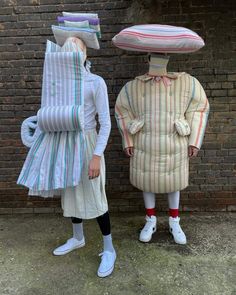 two people dressed in costumes standing next to each other with large objects on their heads