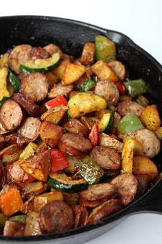 a skillet filled with sausage, peppers and zucchini