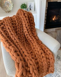 a large chunky blanket sitting on top of a chair next to a fire place