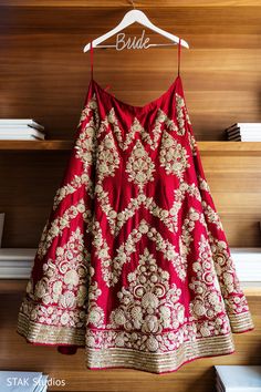 a red and gold dress hanging on a hanger in front of a wooden wall