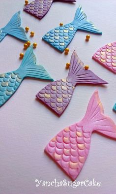 several different colored fish shaped cookies sitting on top of a table