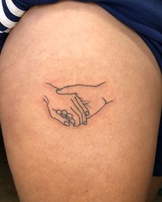 a woman with a tattoo on her thigh holding the hand of another person's arm