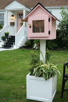 a pink birdhouse sitting on top of a white planter