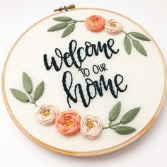 a hand embroidered welcome sign with flowers on it