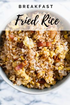 a white bowl filled with fried rice on top of a marble counter next to a fork