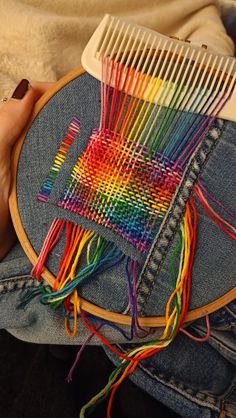 a person is holding a colorful piece of yarn and a comb in their lapel