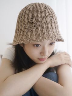 a woman wearing a knitted hat with her hands on her chest and looking at the camera