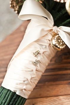 the bouquet is wrapped in white satin and has gold buttons on it's side