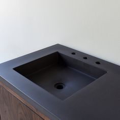 a black bathroom sink sitting on top of a wooden cabinet next to a white wall