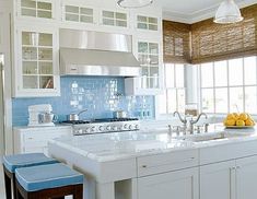 a kitchen with white cabinets and blue backsplash