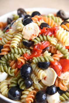 a white bowl filled with pasta salad and olives