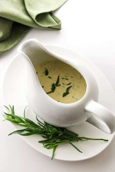 a white saucer filled with soup and garnished with herbs on a plate