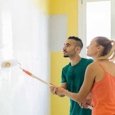 a man and woman are painting the walls together