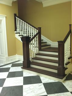 an empty room with black and white checkered flooring, stairs and railings