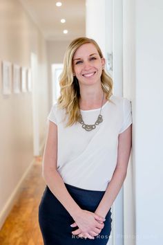 a woman standing next to a white wall in a room with wood floors and walls