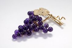 "The 14kt. gold One Leaf and Vine Brooch has a large leaf and a gold runner wire on an 1 1/8\" long vine. The grape cluster has 29 4mm. round natural dark Amethyst gemstones hand mounted to a 14kt. gold grape stem. That is over 3 1/2 carats total weight of Amethyst gemstones! The Cabernet Leaf has a lot of engraved detail as well as engraved detail on the grape stem. The pin on the back is a hinged pin stem with a joint and catch. Overall actual size of this piece is 1 1/2\" tall by 1 1/8\" wide Elegant Purple Brooches For Anniversary, Amethyst Brooch For Anniversary, Amethyst Brooch Jewelry For Anniversary, Elegant Gold Amethyst Brooches, Amethyst Brooch Jewelry Gift, Purple Brooch Jewelry Gift, Elegant Grape Colored Jewelry For Gift, Gold Runner, Dark Amethyst