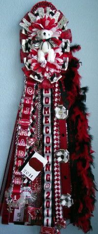 a red and white dress with black feathers on the bottom is hanging up against a wall