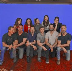 a group of people posing for a photo in front of a blue wall and red carpet