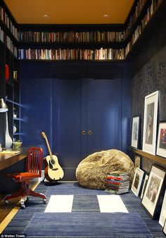 a room with bookshelves full of books and pictures on the wall, including a guitar