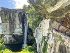 a waterfall is coming out of the side of a cliff into a body of water