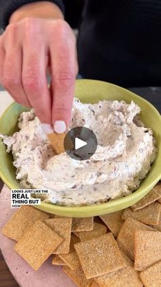 a person dipping some crackers into a bowl of dip