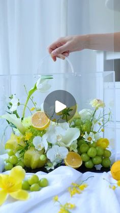 a person is arranging flowers and fruit in a vase