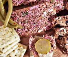 several different types of food on a cutting board next to crackers and pickles