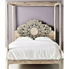 a white bed with an intricate headboard against a purple wall