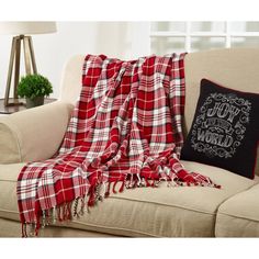 a red and white plaid blanket sitting on top of a couch next to a pillow