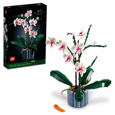 a lego plant with white and pink flowers in it's blue vase next to the box