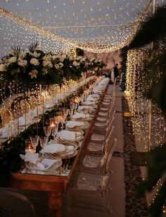 a long table is set up with white flowers and greenery for an outdoor dinner